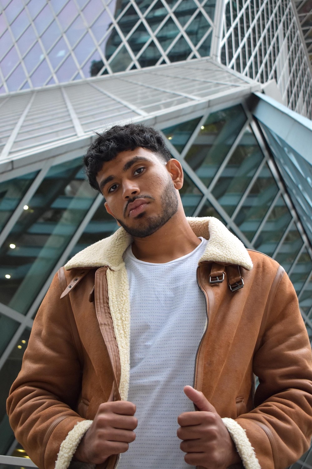 Sree in a shearling jacket in front of the Seattle Central Library, head tilted toward the camera